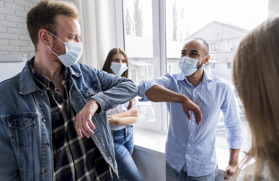 Collègues se saluant durant l'épidémie de la covid 19 avec un masque