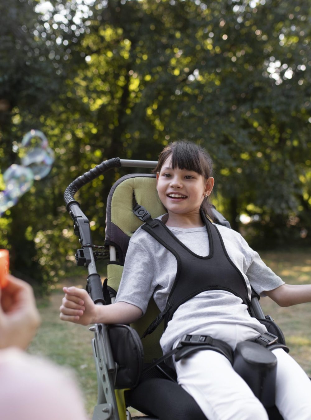 Jeune fille en fauteuil roulant s'amusant avec des bulles
