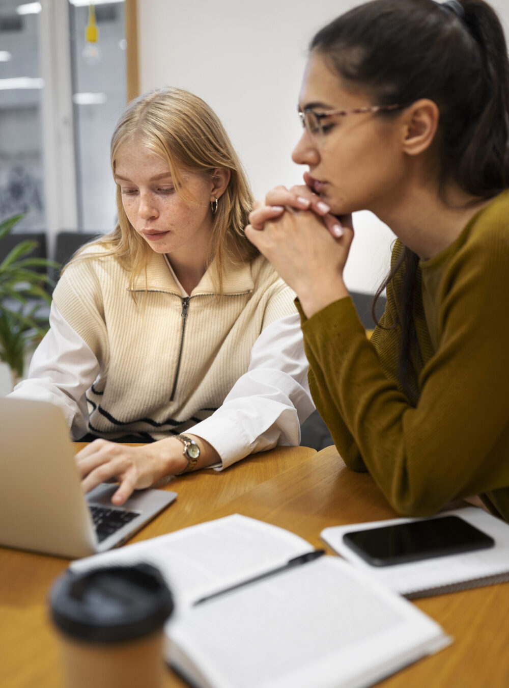 Deux femmes collègues assistant à une formation. L'une d'elle écoute attentivement pendant que l'autre prend des notes