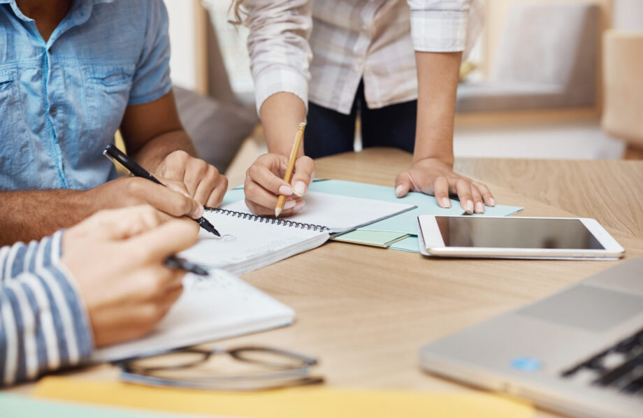 Gros plan sur un bureau lors d'un travail de groupe avec des documents imprimés et des tablettes tactiles